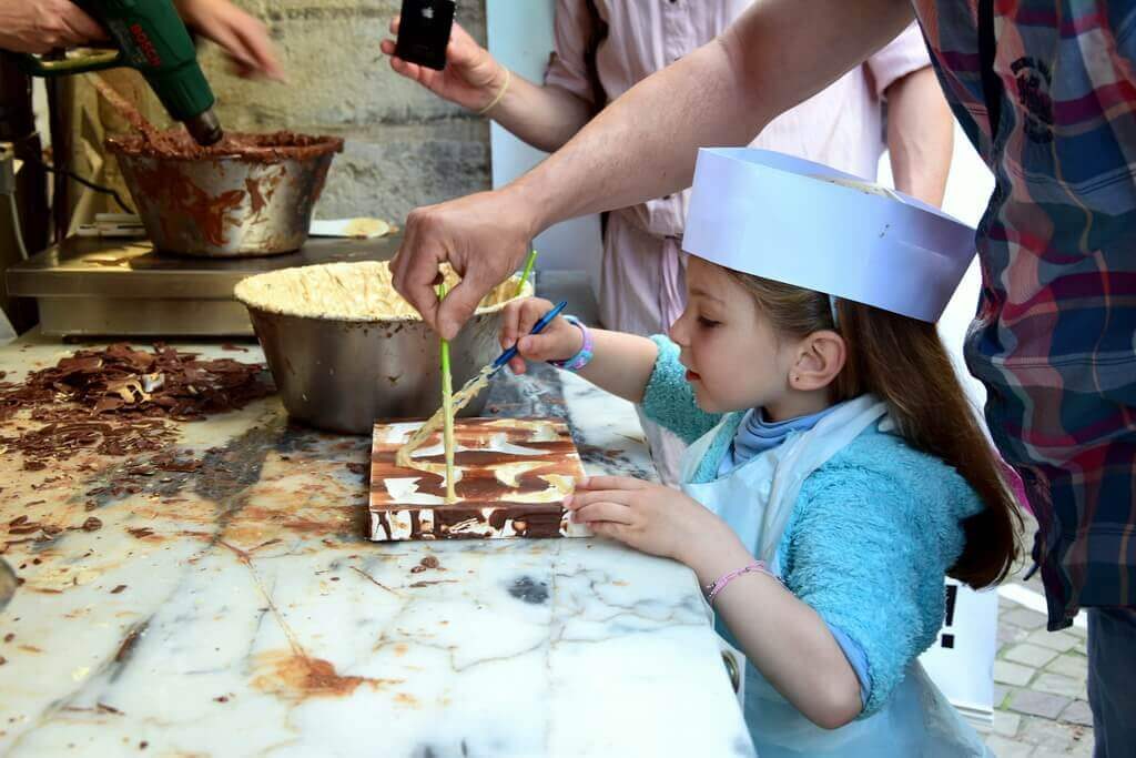 A little girl preparing chocolate balls with the help of her parents