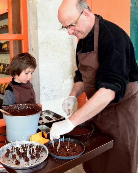 A chocolate Master and his grandson preparing chocolate bites in front of the chocolate factory