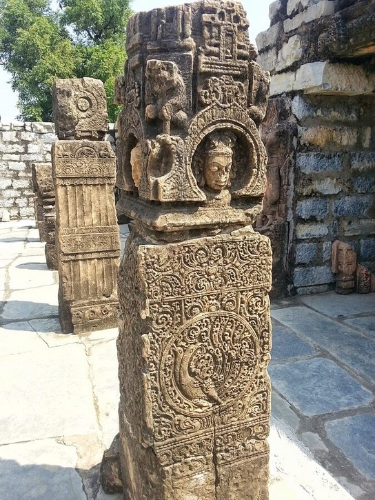 A beautiful pillar with heads on each side at the top and an animal, here a peacock at the bottom