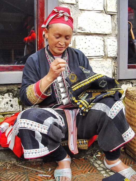 A red Dao woman wearing the traditional clothes and doing handicraft