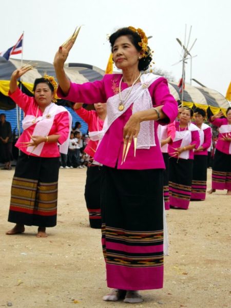 Female dancers wearing a black and pink batik, a pink jacket and long golden nails