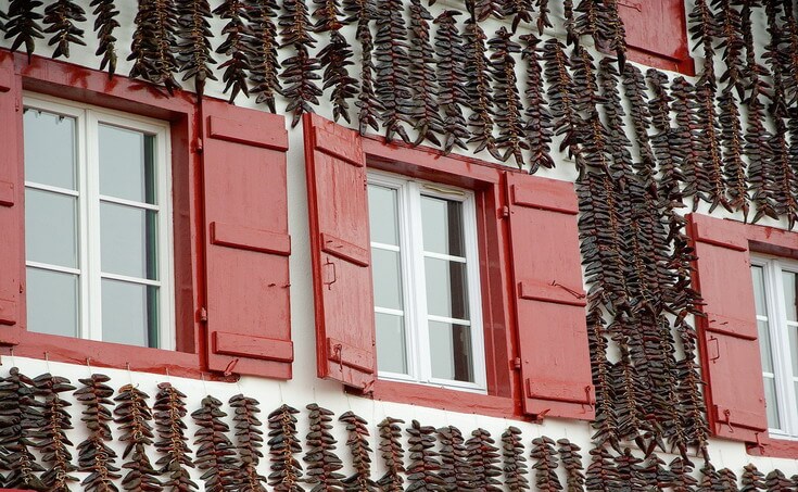 The typical white facade with red shutters decorated with red chilli in Espelette, village of axoa