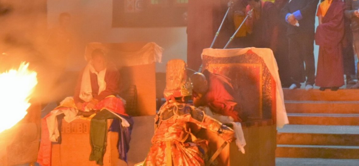 L'oracle bouddhiste tibétain de Dirang accroupi face à un Lama
