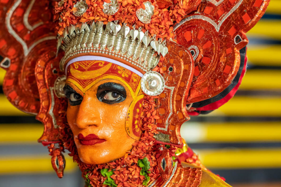 Face of a Theyyam actor with orange, black and red make-up