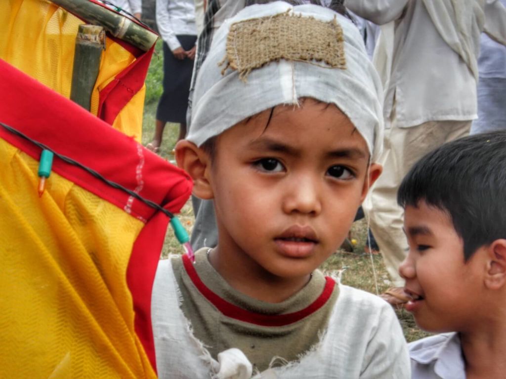 Little boy wearing a white funeral cap