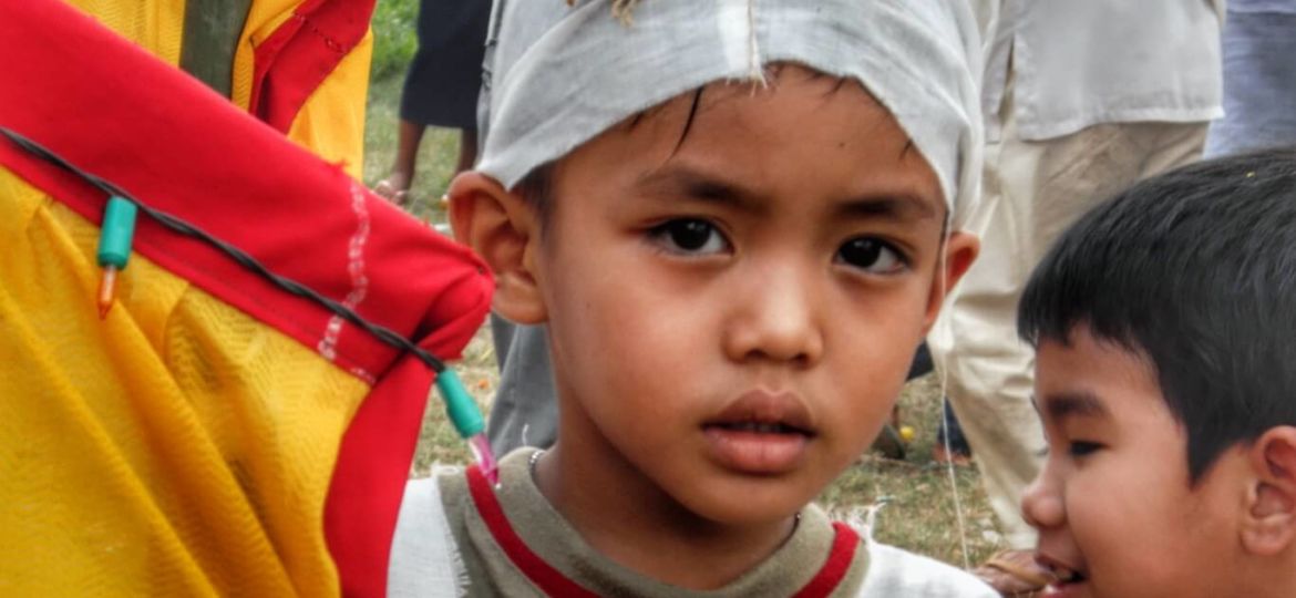 Little boy wearing a white funeral cap