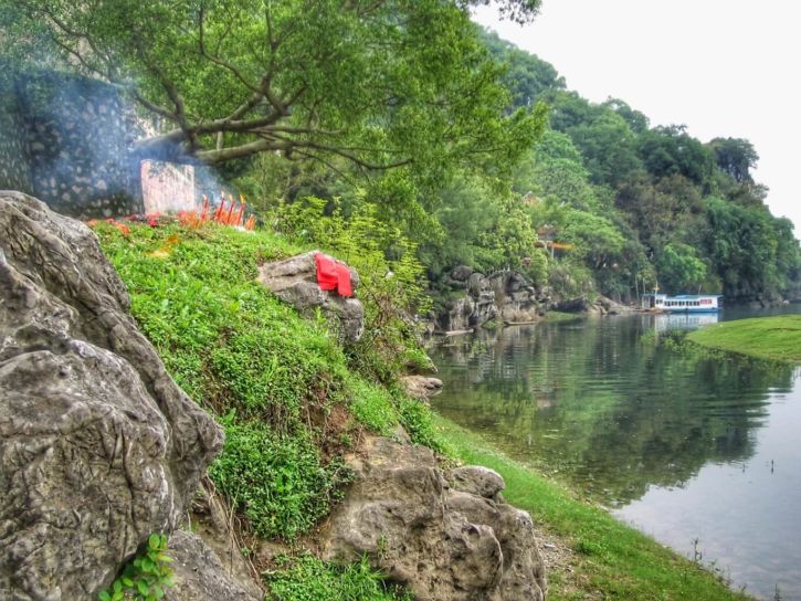 A tomb decorated with red papers and crackers, along Li River