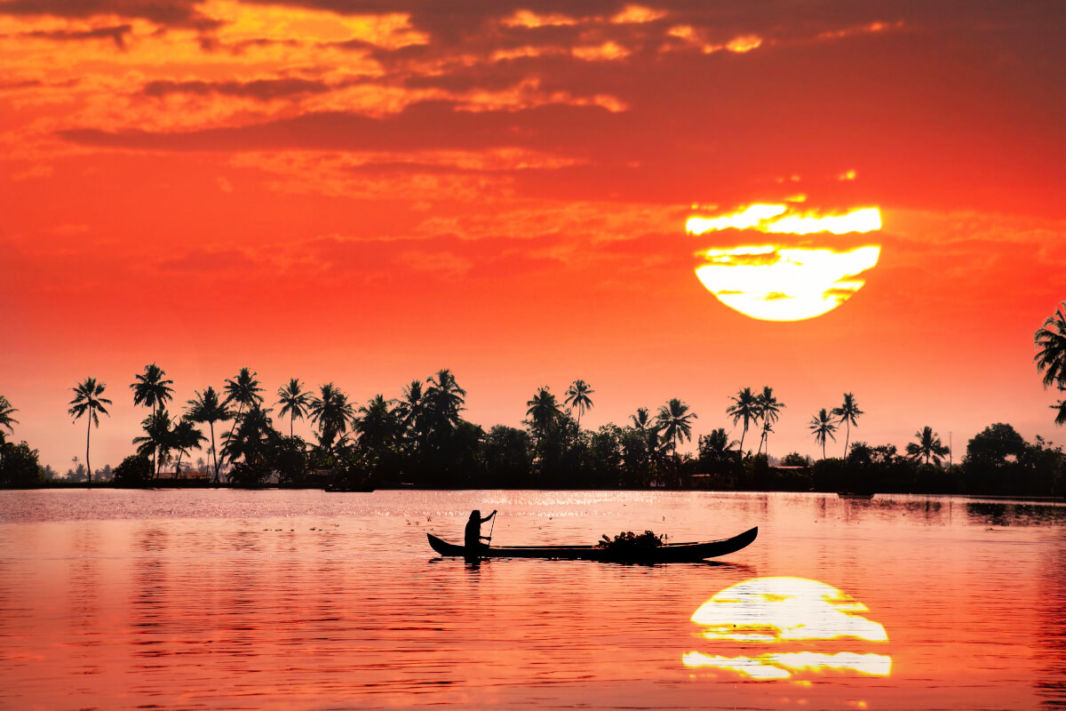 Little boat with Kerala sunset and coconut trees